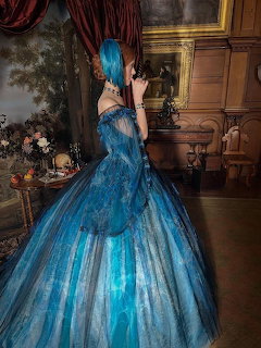 Woman in a dramatic blue ball gown standing in an ornate vintage room