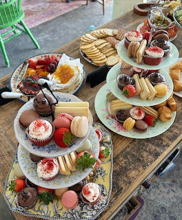 Tiered dessert stands with colorful pastries, cakes, macarons and strawberries on wooden table