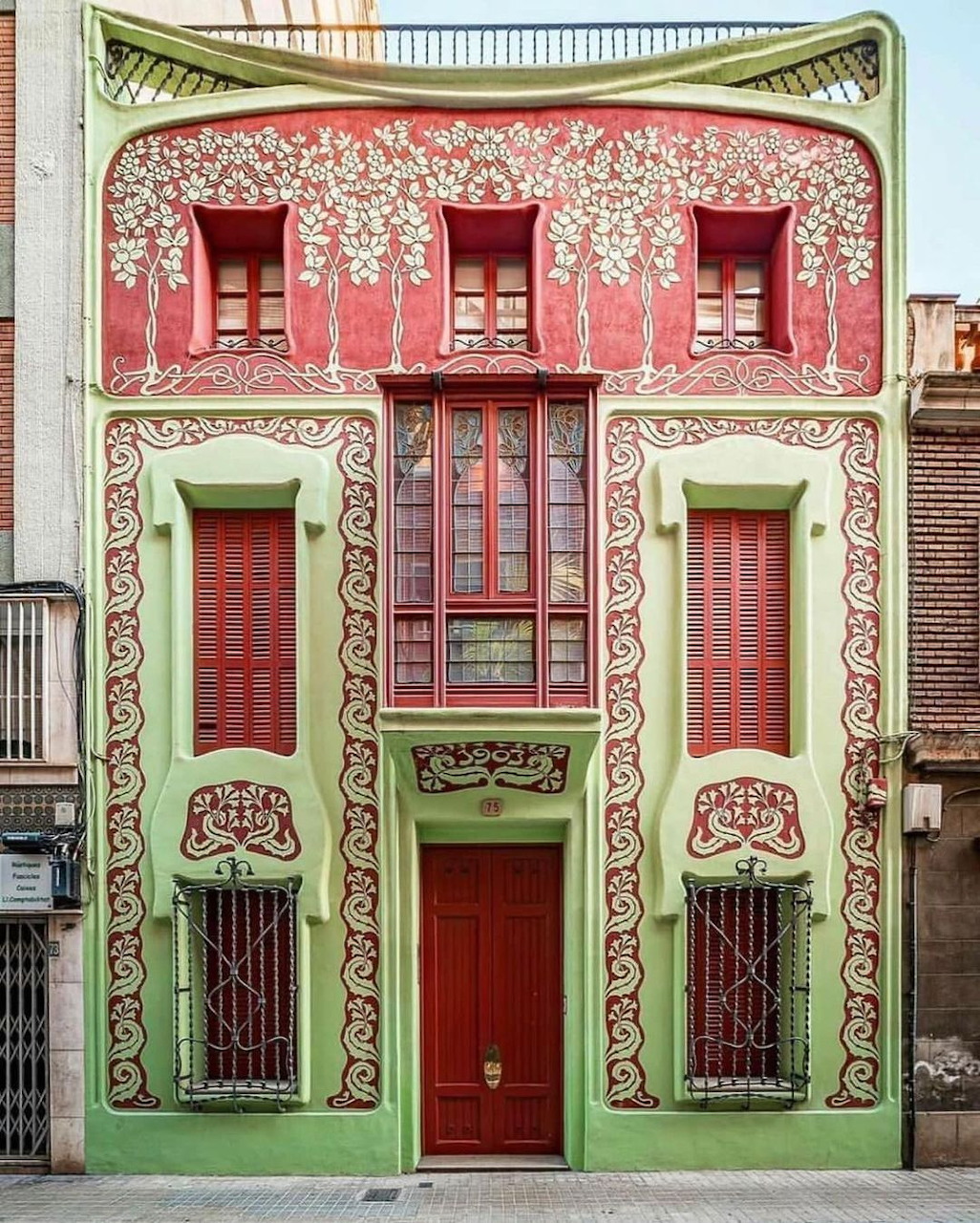 Colorful Art Nouveau building facade with red and green floral decorations and ornate ironwork in Barcelona