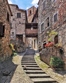 Stone steps ascending narrow alley between old stone buildings in Tuscany