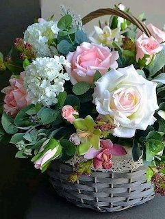 Woven basket with pink and white roses, green orchids, hydrangeas, and eucalyptus greenery