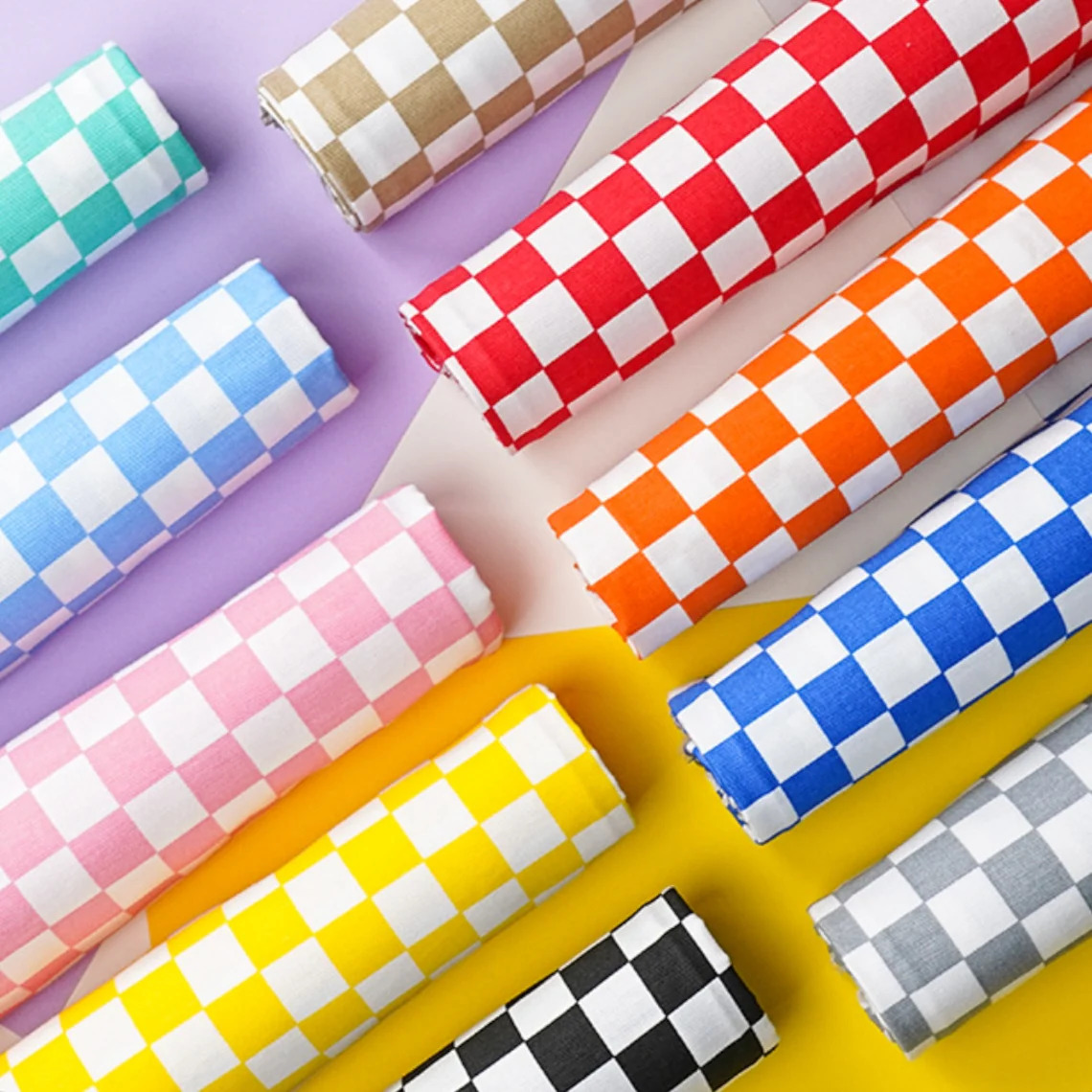 Colorful checkered woven fabric rolls in various rainbow colors arranged diagonally