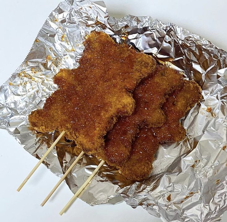 Bear-shaped fried cutlets on skewers with cabbage and sauce on foil