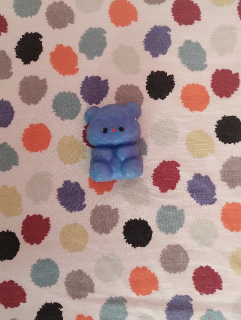 Blue slime bear on white fabric with colorful polka dot pattern
