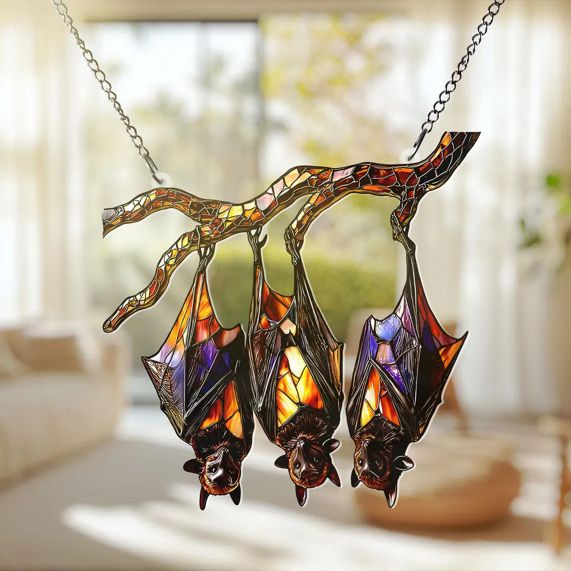 Colorful stained glass bat suncatcher hanging upside down in front of a bright window
