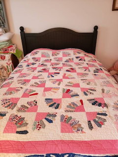 Vintage fan pattern quilt with pink and floral fabric blocks spread on bed