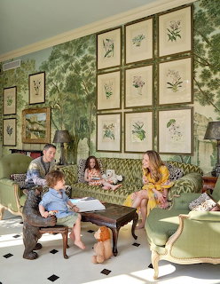 Family sitting in an elegant green living room with botanical art prints on the wall and patterned furniture