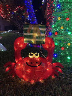 Glowing red crab decoration with lantern among Christmas lights and trees at night