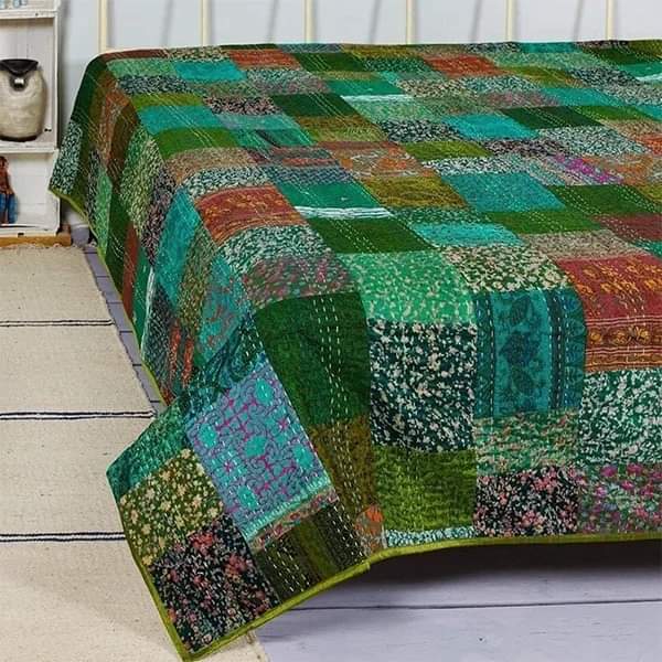 Colorful patchwork quilt with green and teal squares draped over bed