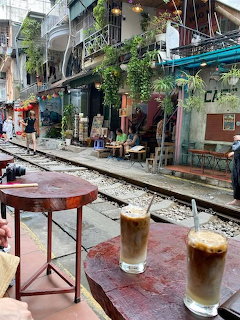 Two iced coffee drinks on a small table beside railway tracks at a Vietnamese street café