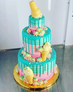 Three-tier turquoise drip cake with ice cream cones and pastel flower decorations
