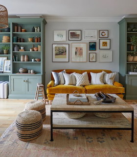 Living room with gold velvet sofa, teal cabinets, gallery wall, rustic coffee table, and woven pouf