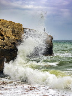 Waves splashing against rocky sea cliffs on the coast at Praia de Albufeira, Portugal