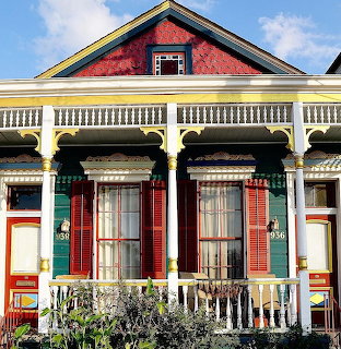 Victorian house with teal walls, red shutters, yellow trim, and white decorative porch