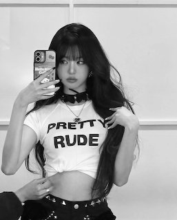 Black and white mirror selfie of young woman in cropped Pretty Rude t-shirt with choker necklace