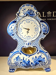 Blue and white Delft porcelain clock with ornate floral decoration and baroque design on dark background