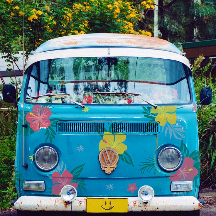 Turquoise VW van with bright flower decals and yellow bumper in garden setting