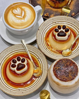 Coffee cups and caramel pudding desserts decorated with cat paw prints on white plates