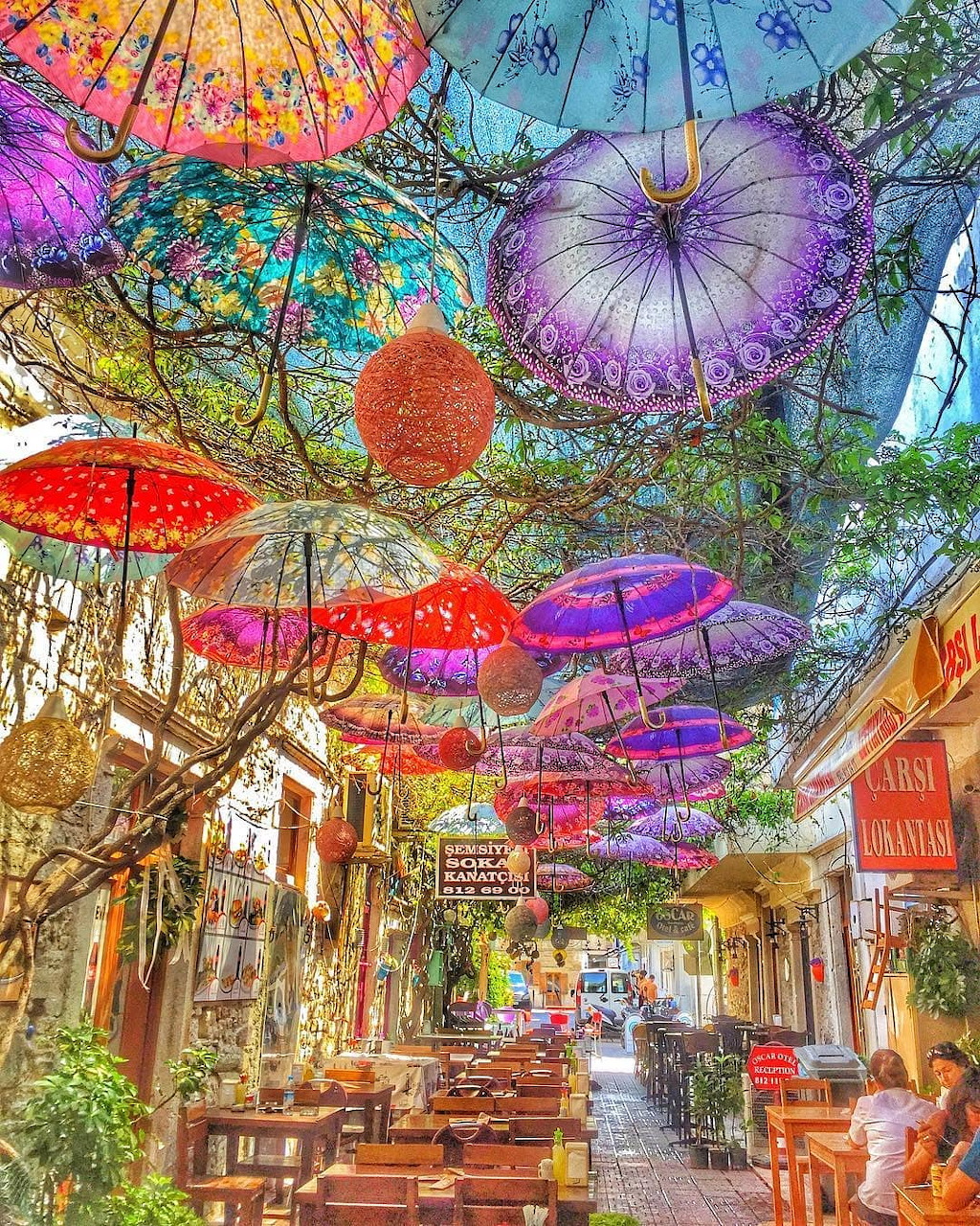 Colorful parasols hanging above outdoor cafe tables in sunny street