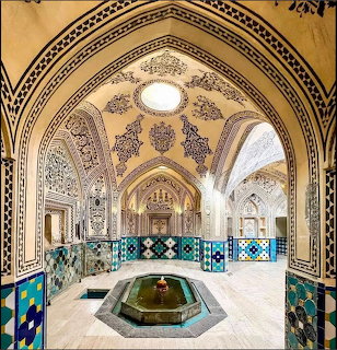 Ornate palace hall with arched ceilings, mosaic tiles, and a central fountain