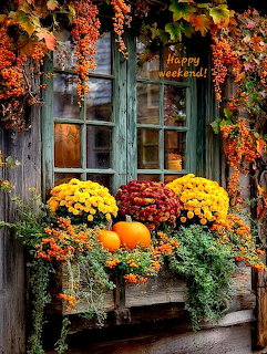 Weathered cottage window decorated with autumn flowers, pumpkins, and vibrant fall leaves