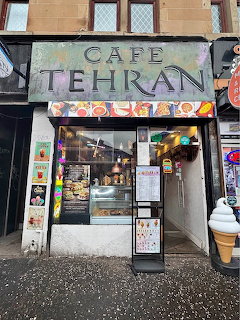 Front of Cafe Tehran storefront with sign, window display, and menu board on a sidewalk
