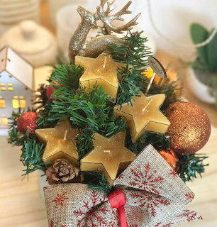 Small Christmas tree decoration with gold stars, pinecones, glitter baubles, and a red bow
