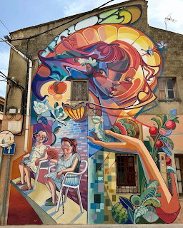 Colorful large-scale street art mural on building wall with surreal female face and vibrant imagery