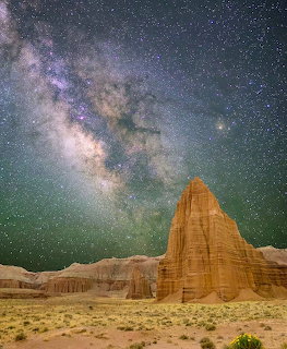Tall orange sandstone tower under starry Milky Way sky in Utah desert