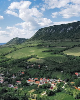 Aerial view of a small village in green valleys below forested mountains in Hungary