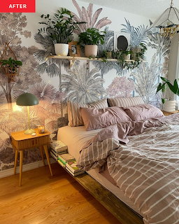 Bedroom filled with tropical plants, wooden bed, pink linens, and warm ambient lighting