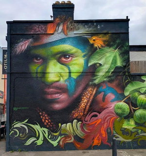 Colorful rainforest-themed face mural painted on a building wall