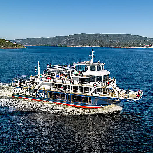 White cruise boat on blue water with distant green hills