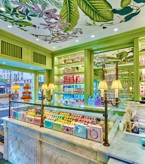 Elegant pastry shop interior with green decor, glass counters, and colorful macarons on display