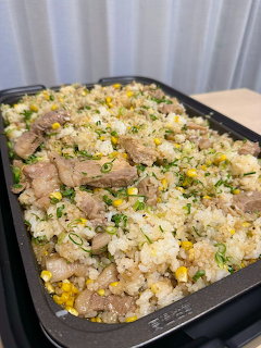 Fried rice with pork, corn, and scallions on black tray