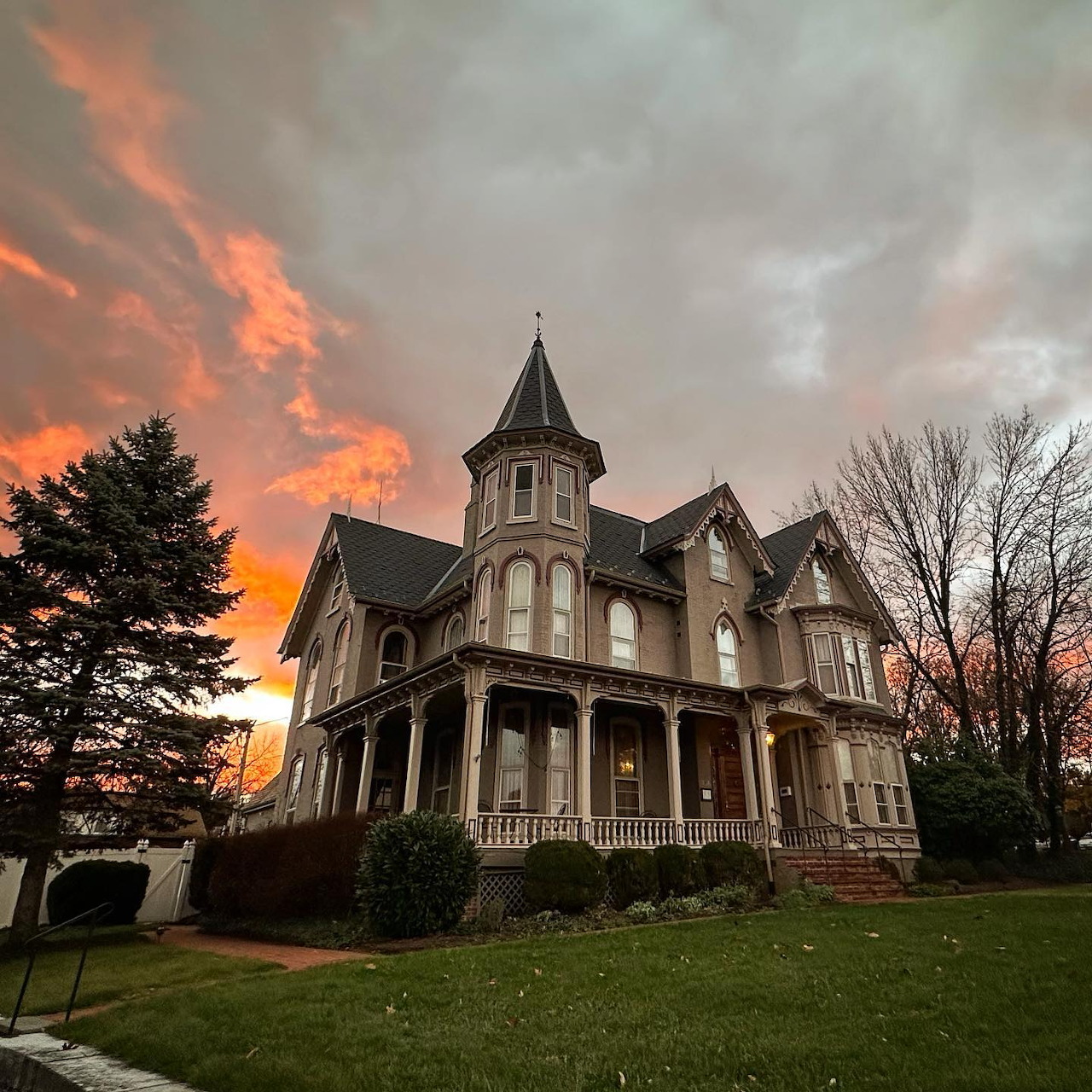 Victorian mansion with tower at sunset with orange clouds