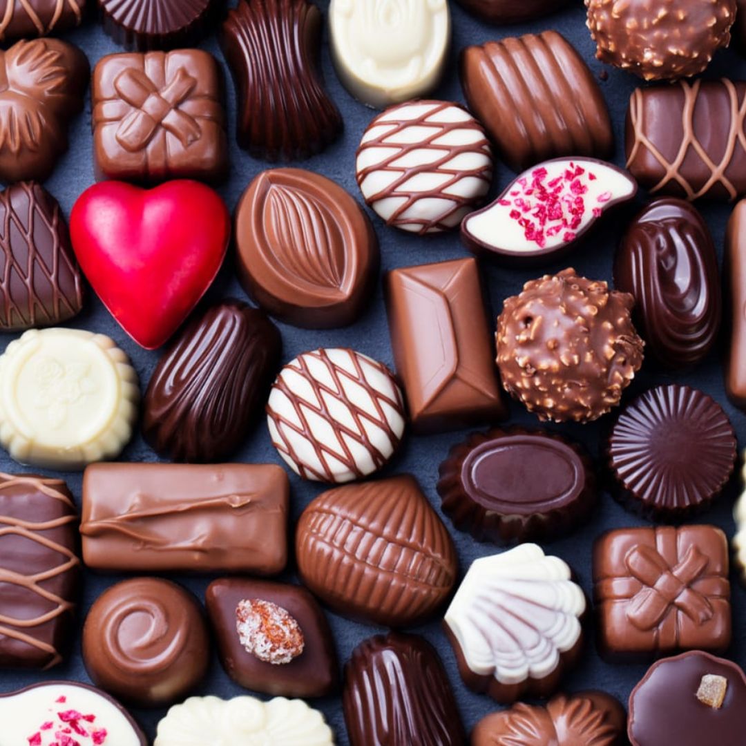 Assorted chocolate candies in different shapes with decorative patterns including hearts, squares, and striped pieces