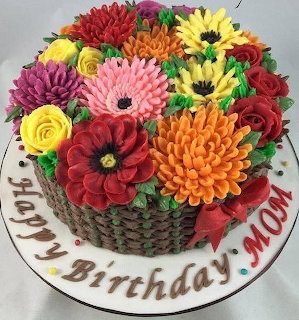 Round birthday cake topped with colorful frosting flowers and Happy Birthday MOM written on the board