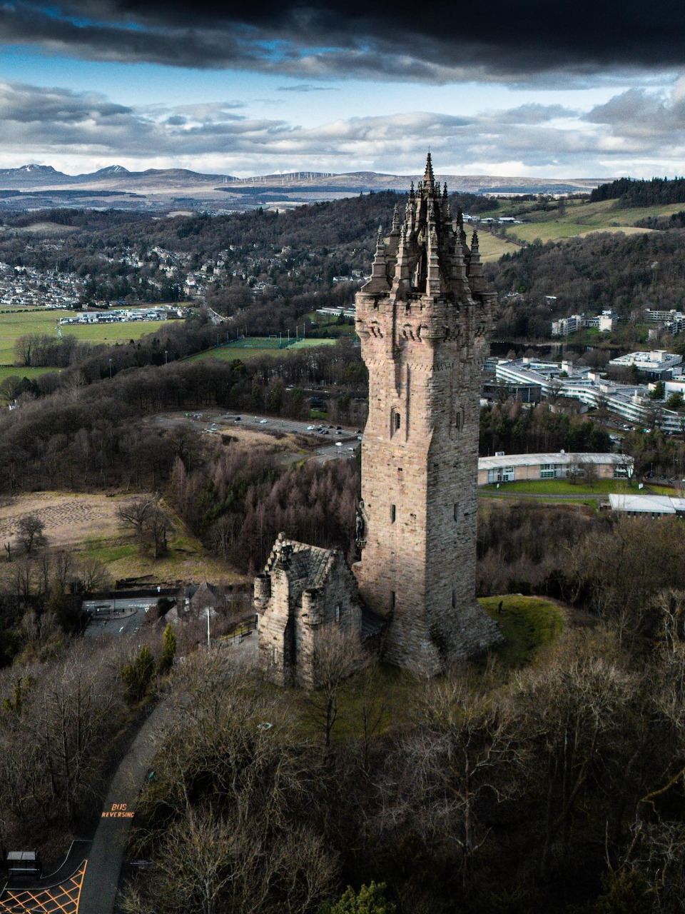 Aerial view of the Wallace Monument tower near Stirling, Scotland, surrounded by trees and rolling landscape