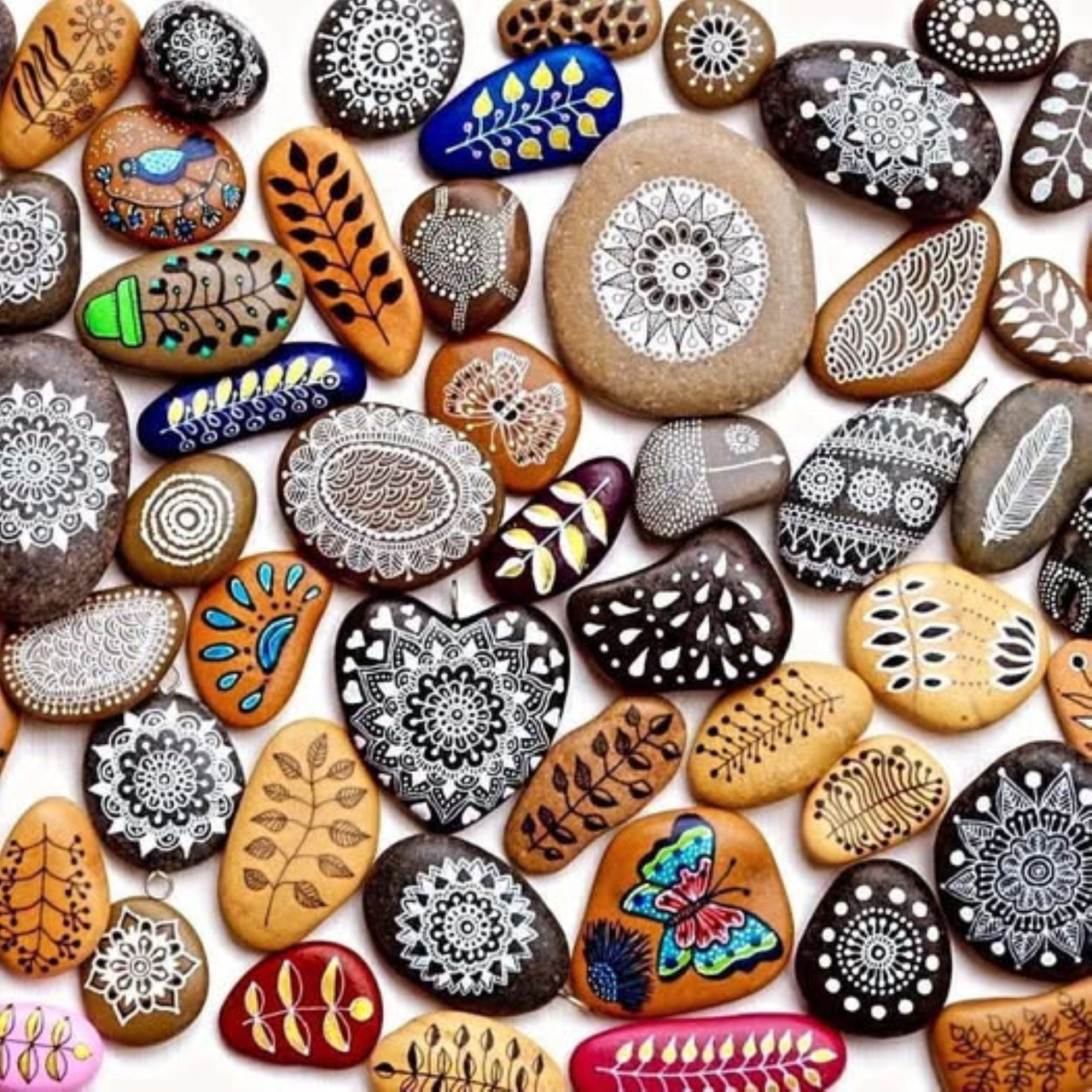 Overhead view of numerous hand-painted decorative stones with mandala and dot patterns in various colors