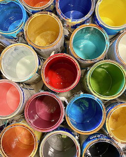 Top view of assorted open paint cans filled with colorful paint