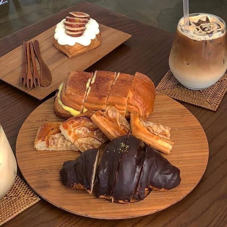 Assorted pastries and iced coffee on wooden plates and a cafe table