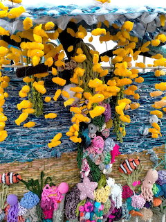 Colorful knitted underwater scene with yellow fish, crocheted coral, starfish, and sea creatures