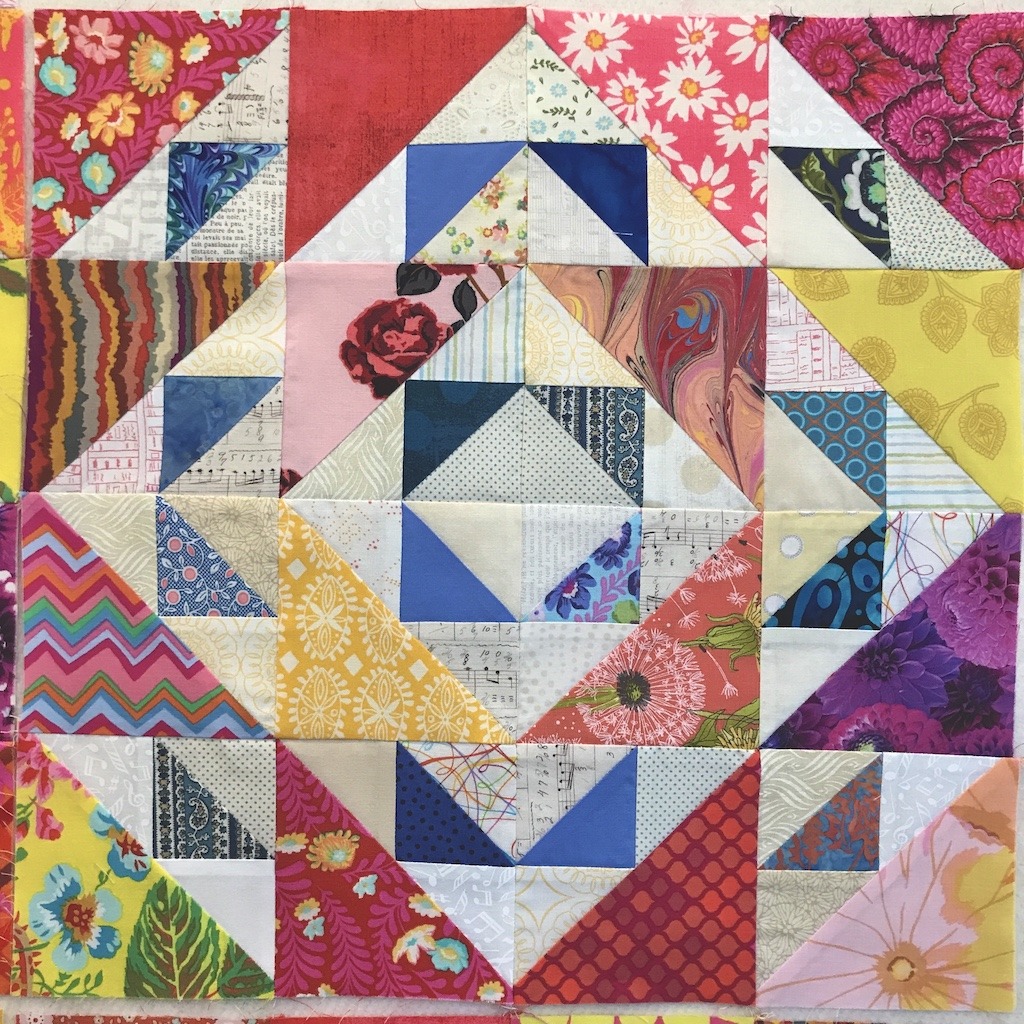 Colorful patchwork quilt with geometric triangle pattern and floral fabrics