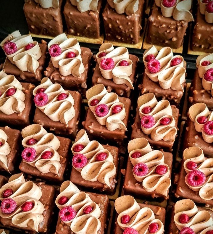 Grid of square pastries with white icing drizzle and pink candy rose decorations