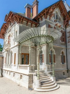 Art Nouveau villa with ornate wrought-iron canopy over entrance steps and decorative stonework