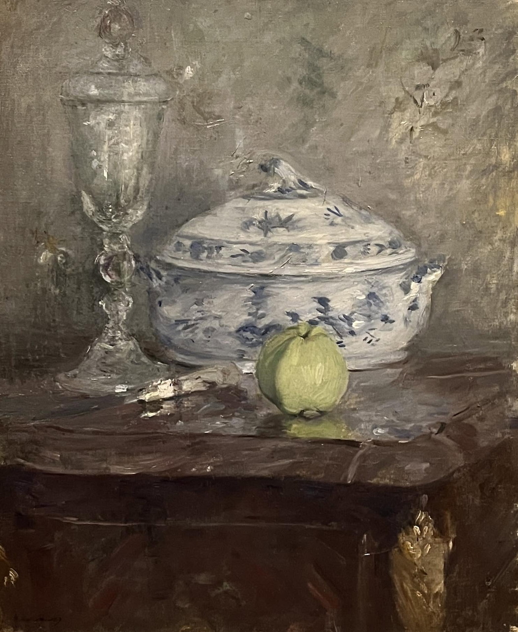 Still life painting with a blue-and-white soup tureen, green apple, and glass on a dark table