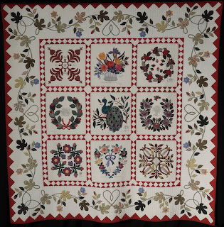 Square patchwork quilt with floral border and nine decorative appliqué blocks
