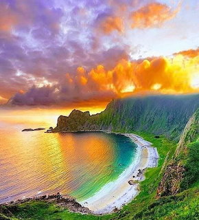 Dramatic sunset over a secluded bay surrounded by steep green cliffs with turquoise water and colorful sky