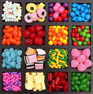 Grid display of assorted colorful candies in individual square compartments